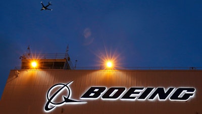 An airplane flies over a sign on Boeing's 737 delivery center, Oct. 19, 2015, at Boeing Field in Seattle.