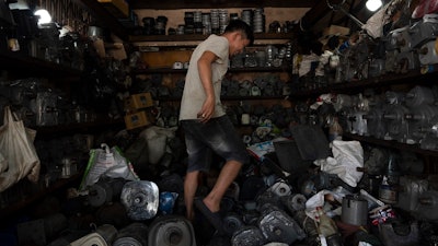 Tu Chi Vy tiptoes through his shop packed with refurbished motors in Nhat Tao Market, the largest informal recycling market in Ho Chi Minh City, Vietnam, on Monday, Jan. 29, 2024.
