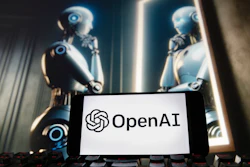 The OpenAI logo is displayed on a cell phone with an image on a computer monitor generated by ChatGPT's Dall-E text-to-image model.
