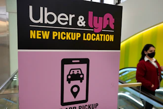 A passerby walks past a sign offering directions to an Uber and Lyft ride pickup location at an airport, Feb. 9, 2021, in Boston.