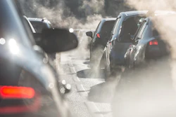 Blurred silhouettes of cars surrounded by steam from the exhaust pipes.