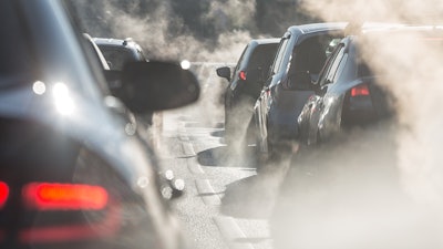 Blurred silhouettes of cars surrounded by steam from the exhaust pipes.