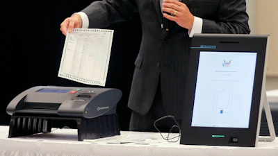 A Smartmatic representative demonstrates his company's system, which has scanners and touch screens with printout options, at a meeting of the Secure, Accessible & Fair Elections Commission.