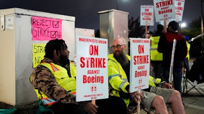 Solomon Hammond, 33, left, and John Olson, 45, right, both toolmakers at Boeing's Renton factory, hold picket signs after union members voted overwhelmingly to reject a contract offer and go on strike Friday, Sept. 13, 2024, outside the company's factory in Renton, Wash.
