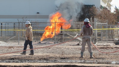 Workers stand near a pipeline fire in Deer Park, Texas, on Thursday, Sept. 19, 2024. The fire had dramatically shrunk in size since it began on Monday, Sept. 16, 2024, and officials said they expected it to be extinguished sometime Thursday evening.