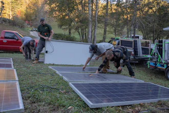 Hayden Wilson, left, Alexander Pellersels, second from left, Jonathan Bowen and Henry Kovacs, right, install a mobile power system at the Beans Creek Church of the Lord Jesus Christ in Bakersville, N.C. on Oct. 9, 2024.