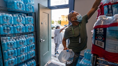 Chris Cowan with Cascadia Behavioral Healthcare's street outreach team loads water and other cooling supplies before visiting homeless camps, Aug. 12, 2021, in Portland, Ore.