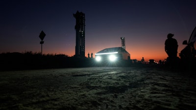 A Tesla Cybertruck passes as the sun sets behind SpaceX's mega rocket Starship, on Oct. 12, 2024, in Boca Chica, Texas.