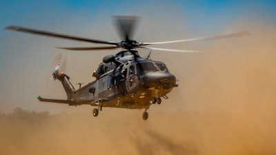 An MH-139A Grey Wolf helicopter lands on a soft dirt field as part of developmental testing.