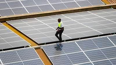 Mark Munyua, CP solar's technician, examines solar panels on the roof of a company in Nairobi, Kenya, Sept. 1, 2023.