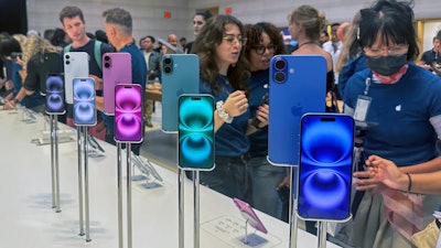 People gather near a display of iPhone 16's at the Apple Store on 5th Ave. in New York on September 20, 2024.