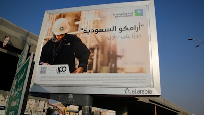 A man walks under a billboard displaying an advertisement for Saudi Arabia's state-owned oil giant Aramco with Arabic reading 'Saudi Aramco, soon on stock exchange' in Jiddah, Saudi Arabia, on Nov. 12, 2019.