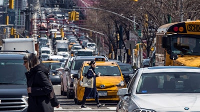 Pedestrians cross Delancey Street as congested traffic from Brooklyn enters Manhattan over the Williamsburg Bridge, March 28, 2019, in New York.