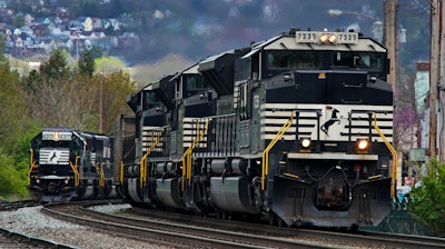 A Norfolk Southern freight train passes a train on a siding as it approaches a crossing in Homestead, Pa, April 27, 2022.