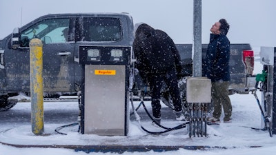Edwin Solomon, 18, at right, stands in the wind and snow while filling up a truck with regular gas at a price of $7.50 a gallon, Wednesday, Oct. 16, 2024, in Kaktovik, Alaska.