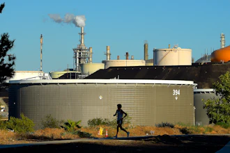 A jogger runs in front of the Phillips 66 refinery, July 16, 2014, in the Wilmington area of Los Angeles.
