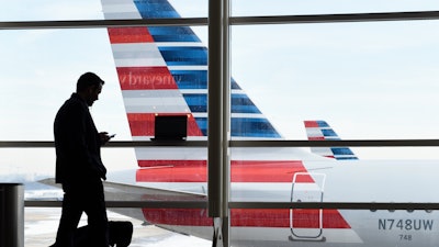 A passenger talks on the phone with American Airlines jets parked behind him at Washington's Ronald Reagan National Airport in Washington, Jan. 25, 2016.
