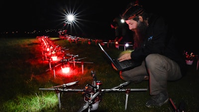 In this handout photo Gabor Vasarhelyi, physicist and researcher of the Department of Biological Physics at Eötvös Loránd University, is using his computer to set a swarm of 100 quadcopters to fly autonomously during an experiment near Budapest, Hungary, Thursday, Oct. 21, 2021.