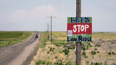 A tractor travels down Hunt Road in front of a 'Let's Stop Lava Ridge' sign near the Minidoka National Historic Site, July 6, 2023, in Jerome, Idaho.