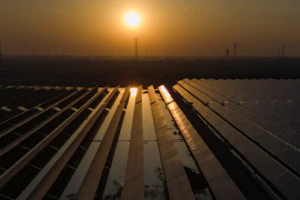 The sun sets over electric pylons along a solar farm near Weifang in eastern China's Shandong province on March 22, 2024.
