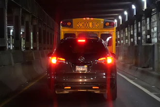 PiggyBack Network co-founder and CEO Ismael El-Amin drives his car behind a Chicago Public Schools bus as on this day he will take three children, including one of his own, to various schools as part of the PiggyBack ride-share network Thursday, Oct. 10, 2024, in Chicago.