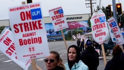 Boeing workers wave picket signs as they strike after union members voted to reject a contract offer near the company's factory in Everett, Washington, Sept. 15, 2024.