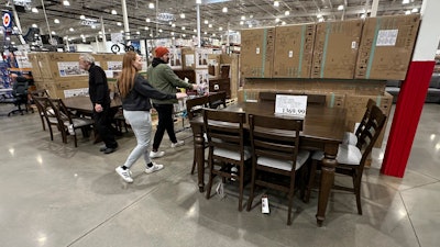 Shoppers pass by a dining room set on display in a Costco warehouse Thursday, Jan. 23, 2025, in Sheridan, Colo.