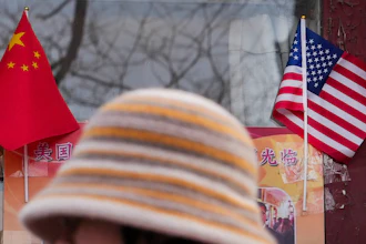 A woman walks by the Chinese and U.S. national flags on display outside a souvenir shop in Beijing on Jan. 31, 2025.