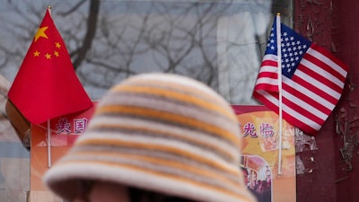 A woman walks by the Chinese and U.S. national flags on display outside a souvenir shop in Beijing on Jan. 31, 2025.