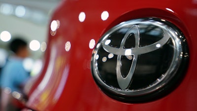 People walk by the logo of Toyota at a show room in Tokyo, Aug. 2, 2019.
