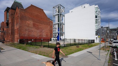 A youth walks a dog past a Last Energy prototype of a microreactor on display at the corner of 10th and V Street NW in Washington, Tuesday, March 25, 2025.
