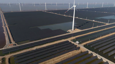 Wind turbines dot the coast line along a giant solar farm near Weifang in eastern China's Shandong province on March 22, 2024.