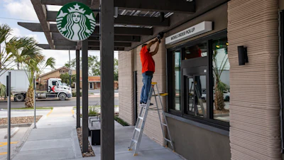 A construction worker adjusts a speaker at a 3D printed Starbucks building Monday, April 28, 2025, in Brownsville, Texas.