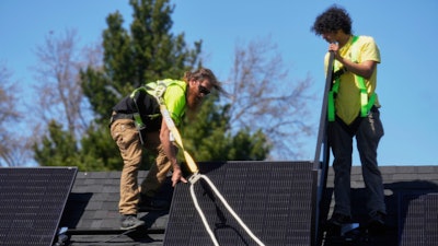 Theodore Tanczuk, left, and Brayan Santos, right, of solar installer YellowLite, work to put panels on a home in Lakewood, Ohio, Wednesday, April 16, 2025.