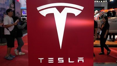 People pass by a Tesla sign at the Manila International Auto Show in Pasay city, Philippines Friday, April 11, 2025.