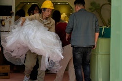 A worker removes plastic sheets after setting up a booth at a mall in Beijing, Wednesday, May 7, 2025.