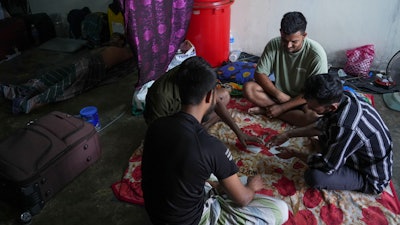 Bangladeshi migrant workers play cards in a dormitory in Klang, Malaysia, Friday, Jan. 24, 2025.