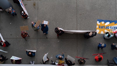 People hold signs during a protest outside the annual Alaska Sustainable Energy Conference on Tuesday, June 3, 2025, in Anchorage, Alaska.