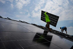 Nicholas Hartnett, owner of Pure Power Solar, carries a panel as he and Brian Hoeppner, right, install a solar array on the roof of a home in Frankfort, Ky., July 17, 2023.