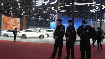 Security personnel on duty stand near the BYD booth during the Shanghai auto show, April 23, 2025.