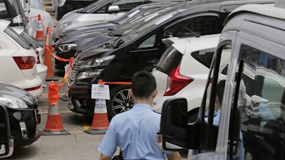 Impounded vehicles meant for Uber service, center, are parked behind a police cordon line at a police station in Hong Kong, Tuesday, May 23, 2017.