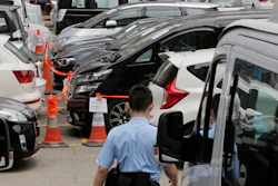 Impounded vehicles meant for Uber service, center, are parked behind a police cordon line at a police station in Hong Kong, Tuesday, May 23, 2017.