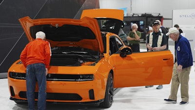 Shoppers look over a 2025 Dodge Charger Daytona hardtop in the Stellantis display at the Colorado Auto Show, April 17, 2025, in Denver.