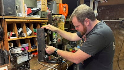 Patrick Schlott repairs an old pay phone in his basement workshop on July 16, 2025, in Williamstown, Vt.