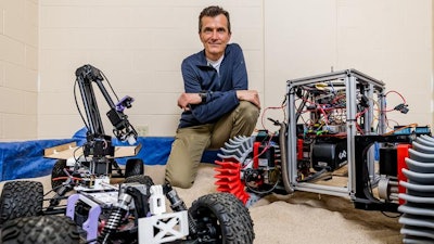 Mechanical engineering professor Dan Negrut poses with a space rover used for testing.
