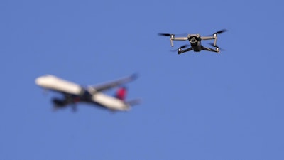 A drone hovers in airspace outside the safety perimeter surrounding St. Louis Lambert International Airport as an airliner approaches for a landing on March 10, 2025.
