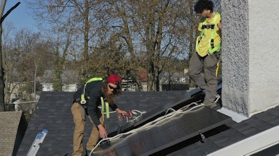 Theodore Tanczuk, left, and Brayan Santos, of solar installer YellowLite, put solar panels on the roof of a home in Lakewood, Ohio, April 17, 2025.
