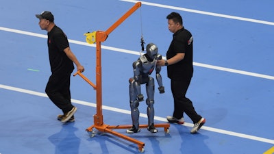 Workers transfer a robot before the opening ceremony for the World Humanoid Robot Games held in Beijing, China, Thursday, Aug. 14, 2025.