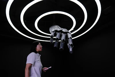 A staff walks in front of robotic arm at the Robot Mall, World's first embodied intelligent robot 4S store in Beijing, China, Wednesday, Aug. 6, 2025.