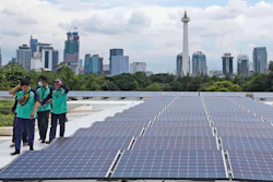 Workers walk near solar panels that provide partial electrical power to Istiqlal Mosque as the city skyline is seen in the background, in Jakarta, Indonesia, Wednesday, March 29, 2023.